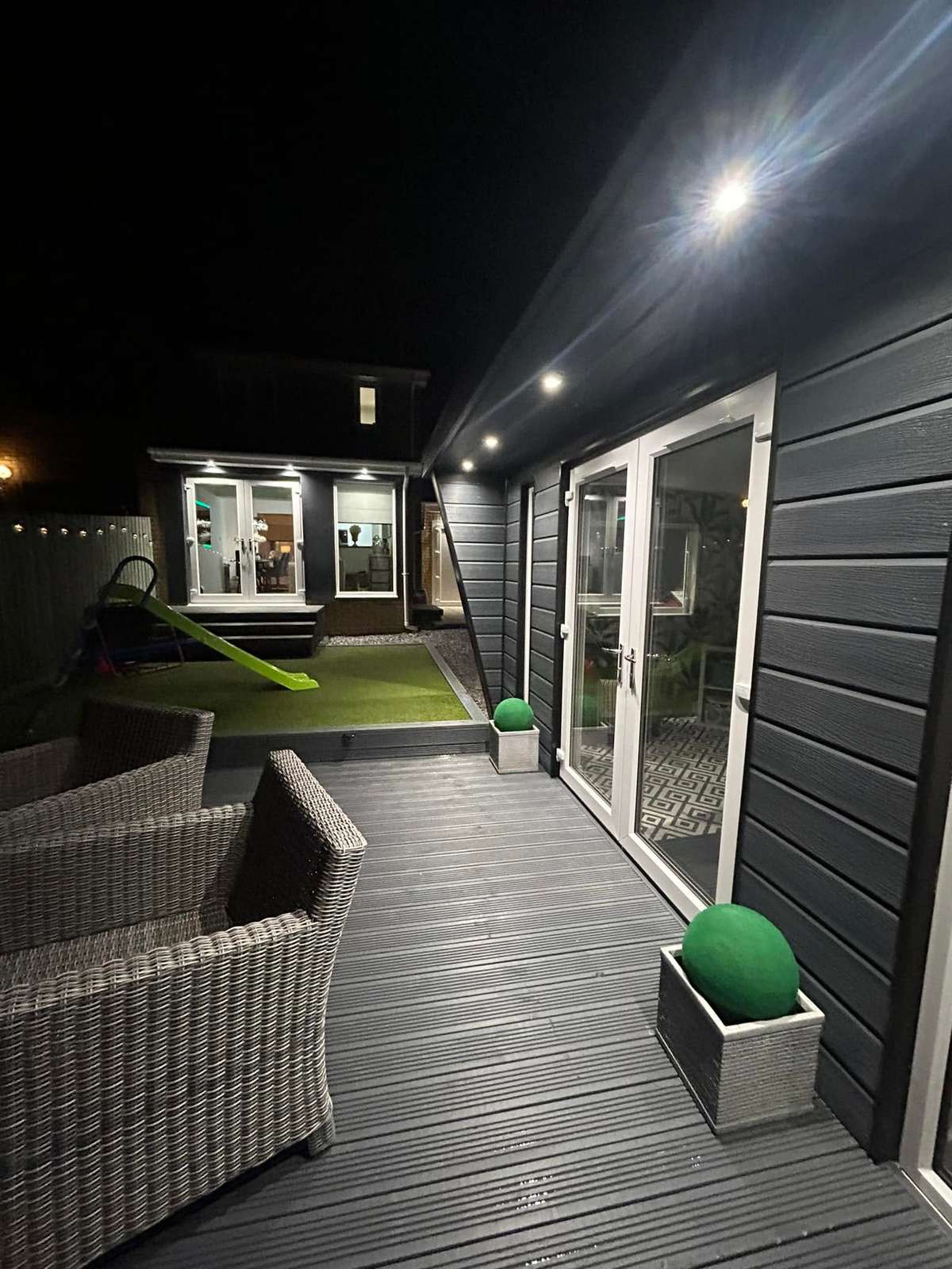 Side of a garden room with decking, at night
