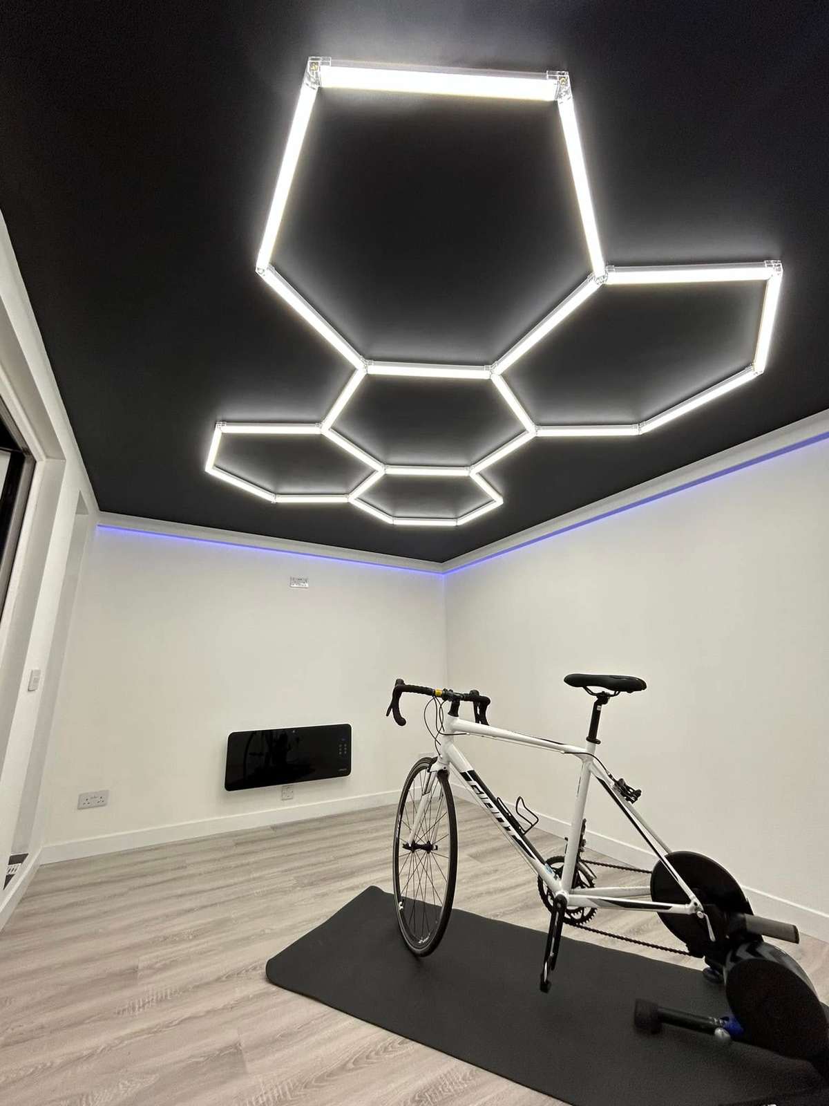 Room with hexagon ceiling lights and a bike in the corner