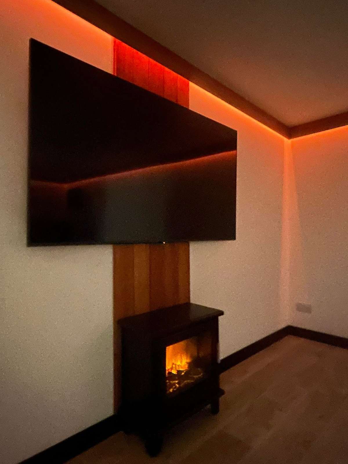 Room with a television, a stove, and warm orange LED light